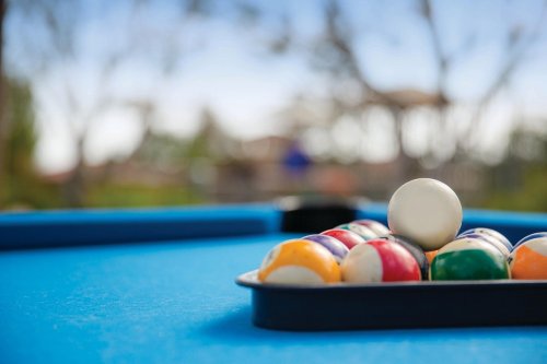 A close-up of a pool table with a rack of colorful billiard balls on a blue felt surface.