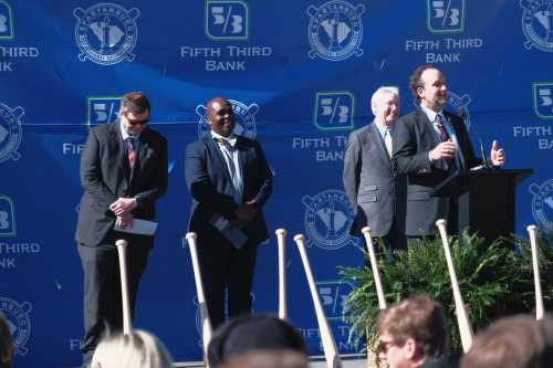 A group of speakers at a podium during an event, with a blue backdrop featuring the Fifth Third Bank logo.