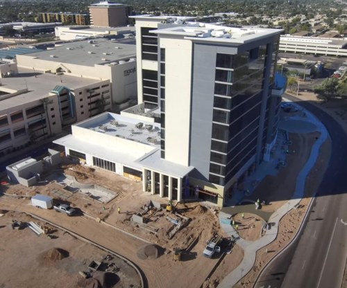Aerial view of a construction site featuring a multi-story building and surrounding landscaping work.