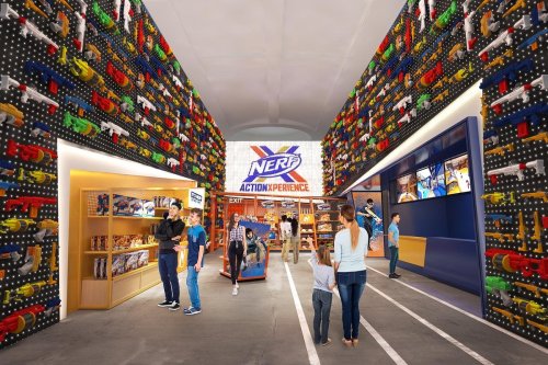 A vibrant indoor space filled with colorful toy blasters, featuring displays, screens, and families enjoying the experience.
