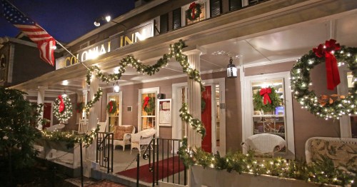 A festive inn decorated with wreaths and lights for the holidays, featuring an American flag and a welcoming porch.