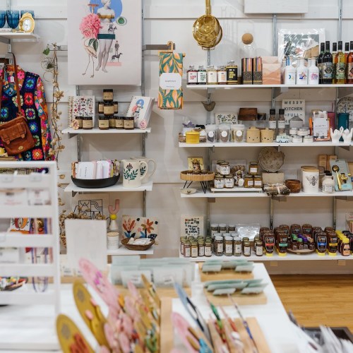 A colorful shop display featuring various home goods, art, and gifts on shelves and tables.