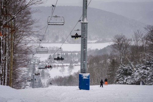 A snowy ski resort scene with a chairlift, skiers, and a winter landscape in the background.