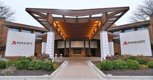 Entrance of a Marriott hotel featuring a modern design with a large overhang and landscaped surroundings.