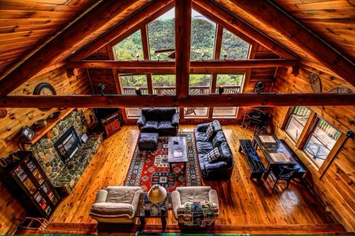 Cozy wooden cabin interior with a spacious living area, large windows, and a view of nature outside.