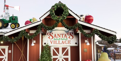 A festive building decorated with garlands, featuring a sign that reads "Santa's Village" and holiday-themed ornaments.