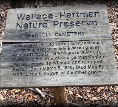 Wooden sign at Ferrell Cemetery in Wallace-Hartman Nature Preserve, detailing the history of the Ferrell family graves.
