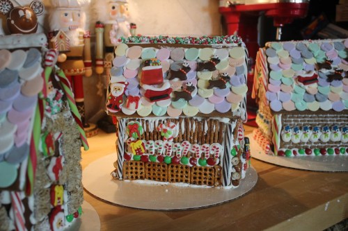 Colorful gingerbread houses decorated with icing, candy, and festive details, set against a cozy holiday backdrop.