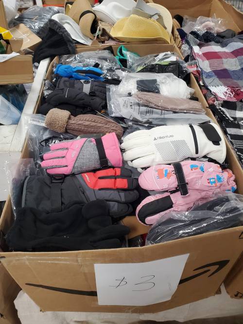 A cardboard box filled with various gloves, including colorful winter gloves, for sale at $3 each.