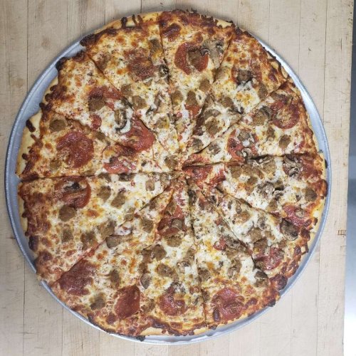 A large pizza topped with pepperoni, sausage, mushrooms, and melted cheese, sliced into equal pieces on a metal tray.