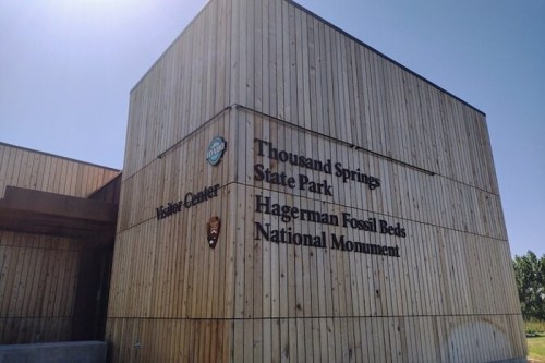 Wooden building exterior with signs for Thousand Springs State Park and Hagerman Fossil Beds National Monument Visitor Center.