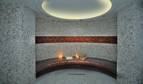 A serene spa room with curved mosaic benches, soft lighting, and candles creating a relaxing atmosphere.