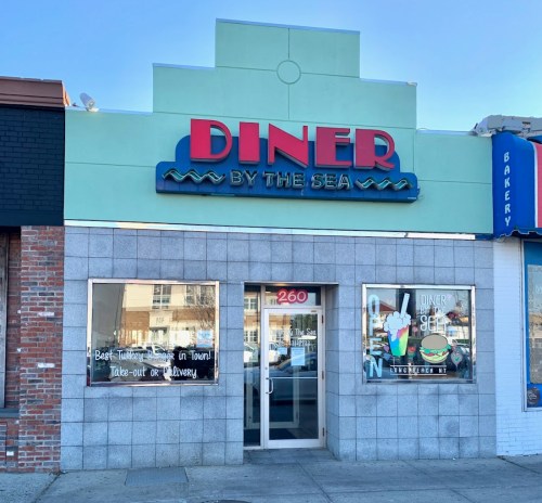 A colorful diner facade with "Diner by the Sea" sign, featuring large windows and a welcoming entrance.
