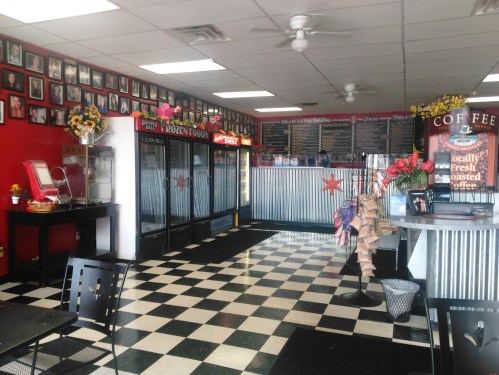 Interior of a diner with checkered floor, colorful walls, and a counter displaying coffee and frozen food options.
