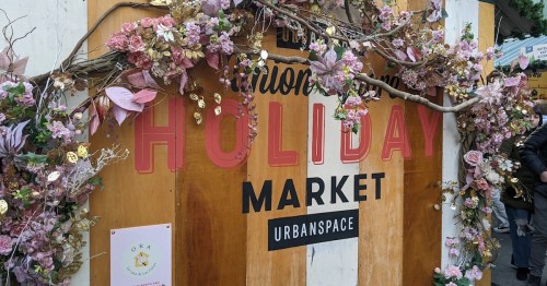 Sign for "Holiday Market" at Urbanspace, decorated with flowers and foliage.