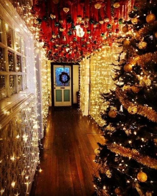 A festive hallway decorated with Christmas lights, ornaments, and a tree, creating a warm holiday atmosphere.