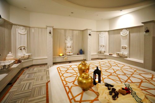 A serene room with a statue, decorative bowls, and golden pots on a patterned floor, creating a peaceful ambiance.
