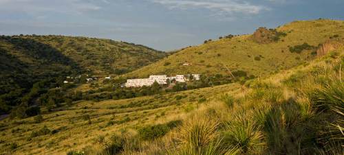 A scenic view of rolling green hills with a cluster of white buildings nestled in the valley.