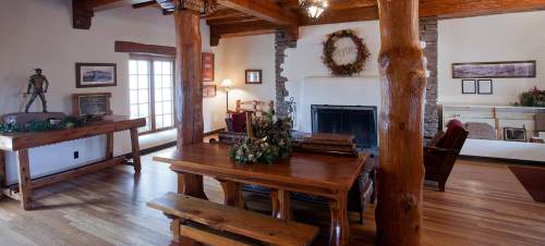 Cozy interior featuring wooden beams, a fireplace, a dining table, and rustic decor in a warm, inviting space.