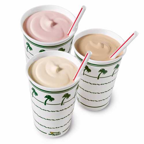 Three milkshakes in paper cups with palm tree designs, featuring pink, white, and brown flavors, each with a straw.