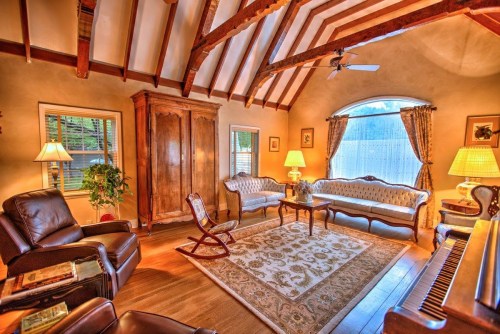 Cozy living room with wooden beams, elegant furniture, a rocking chair, and a large window letting in natural light.