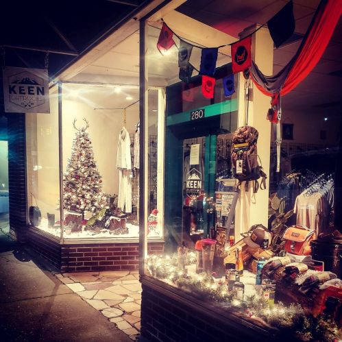 A storefront decorated for the holidays, featuring a Christmas tree and outdoor gear displays.