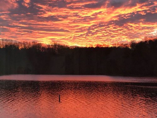 Vibrant sunset over a calm lake, with colorful clouds reflecting on the water's surface.