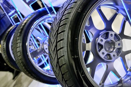 Close-up of car wheels and tires displayed with blue lighting, showcasing different tread patterns and designs.
