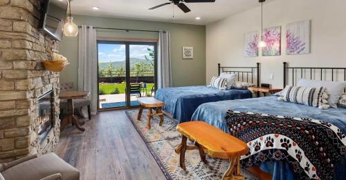 Cozy hotel room with two beds, a stone fireplace, and a view of nature through sliding glass doors.