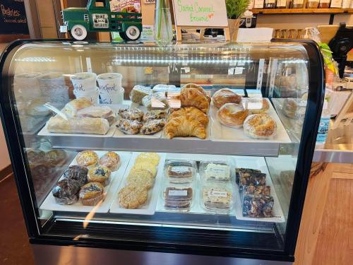 A display case filled with various baked goods, including pastries, cookies, and croissants, in a cozy café setting.