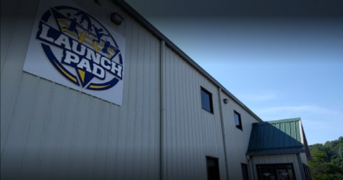 Exterior of a building with a large "Launch Pad" sign, featuring a blue and yellow logo against a gray metal facade.