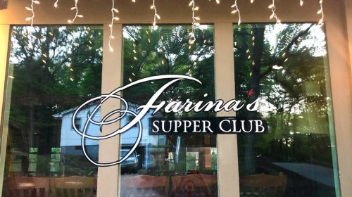 Sign for "Farina's Supper Club" on a window, surrounded by trees and decorative string lights.