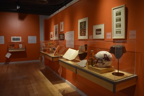 Exhibit featuring sports memorabilia and historical artifacts displayed in a brightly colored gallery.