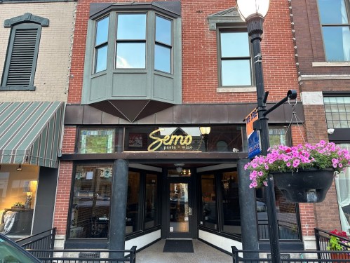 Exterior of Semo restaurant, featuring a brick facade, large windows, and hanging flower baskets.