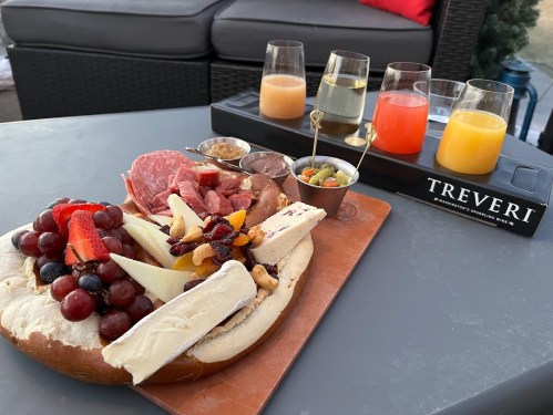 A charcuterie board with meats, cheeses, fruits, and nuts, accompanied by colorful drinks on a table outdoors.