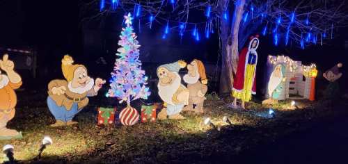 Colorful holiday display featuring cartoon characters, a Christmas tree, and lights in a festive outdoor setting.