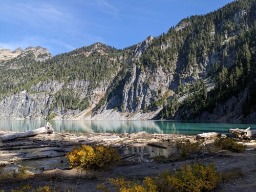 A serene lake surrounded by mountains and trees, with colorful autumn foliage in the foreground.