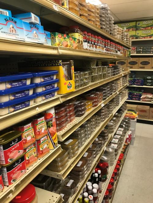 A grocery store aisle filled with various spices, sauces, and packaged foods on shelves.