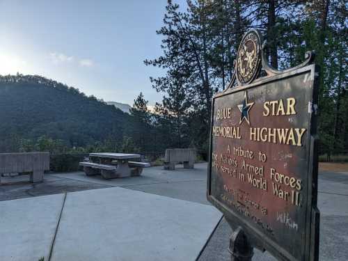 Sign for Blue Star Memorial Highway with a scenic view of mountains and trees in the background.