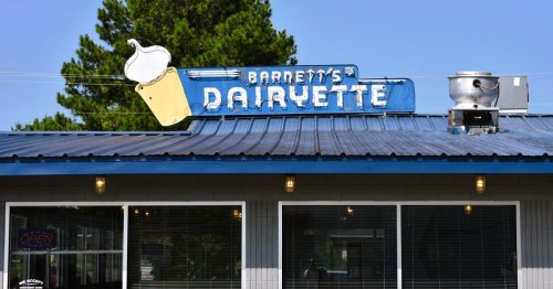 Exterior of Barnett's Dairyette, a retro restaurant in AR, featuring a blue sign with a soft serve ice cream cone.