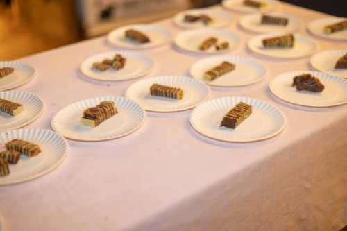 A table covered with a cloth displaying multiple plates, each holding small pieces of layered dessert.