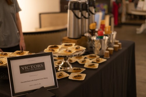 A table set with coffee dispensers and plates of chocolate desserts, featuring a sign for Victors Seafood.
