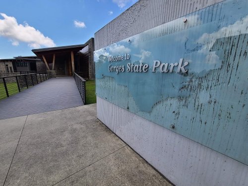 Sign at the entrance of Gorges State Park, featuring a modern design and a pathway leading to the visitor center.