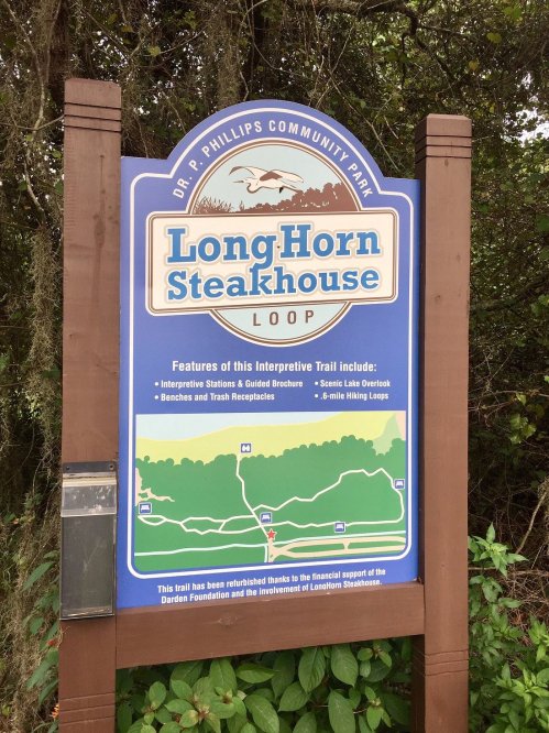 Sign for LongHorn Steakhouse Loop at Dr. P. Phillips Community Park, detailing trail features and support information.