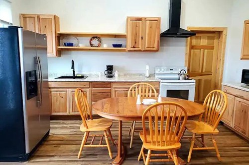 A cozy kitchen featuring wooden cabinets, a round table with chairs, and modern appliances.