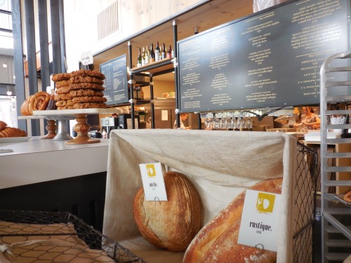 A bakery display featuring loaves of bread and cookies, with a menu board in the background.