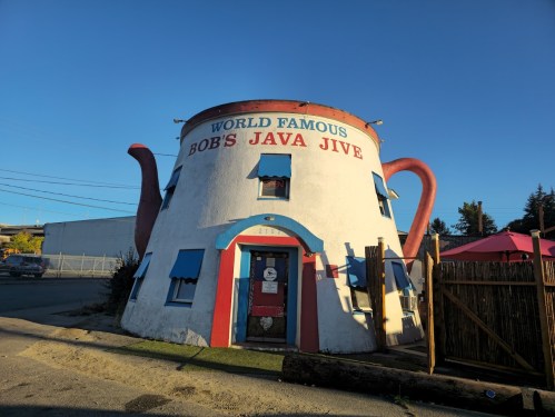 A whimsical teapot-shaped building with "Bob's Java Jive" sign, featuring colorful windows and a welcoming entrance.