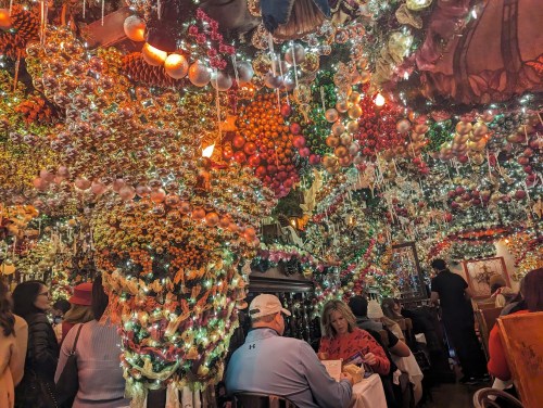 A festive restaurant interior adorned with colorful ornaments and lights, filled with diners enjoying their meals.