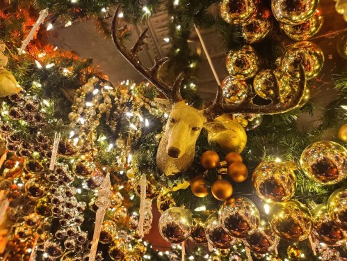 A festive display featuring a reindeer head surrounded by golden ornaments and sparkling icicles.