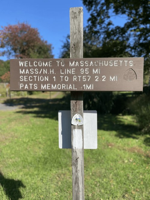 Signpost indicating the welcome to Massachusetts, with distances to the NH line and nearby sections.